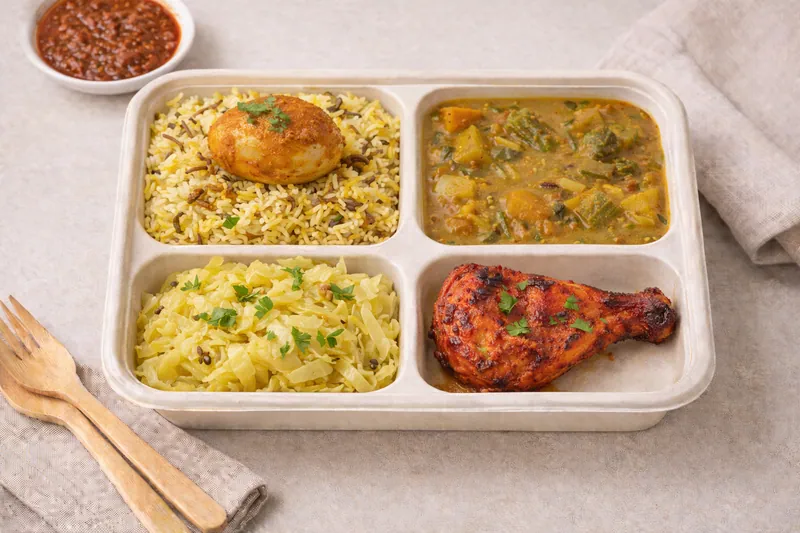 Healthier choice halal bento with basmati biryani, dalchar, cabbage sabzi, tandoori chicken and curry egg